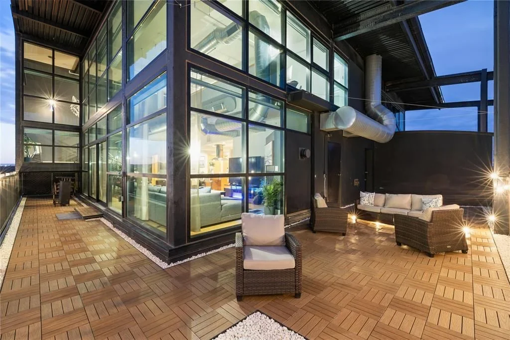 Private terrace at penthouse 1202 beside the illuminated living area at dusk