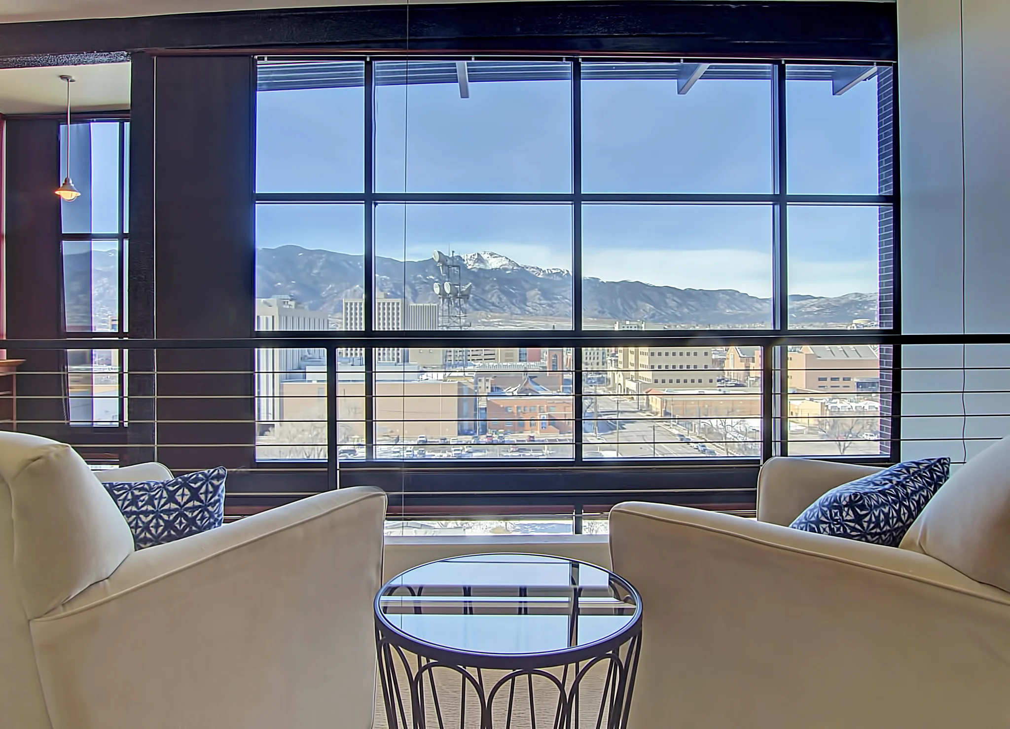 Two chairs beside a window looking toward Pikes Peak in penthouse 1204
