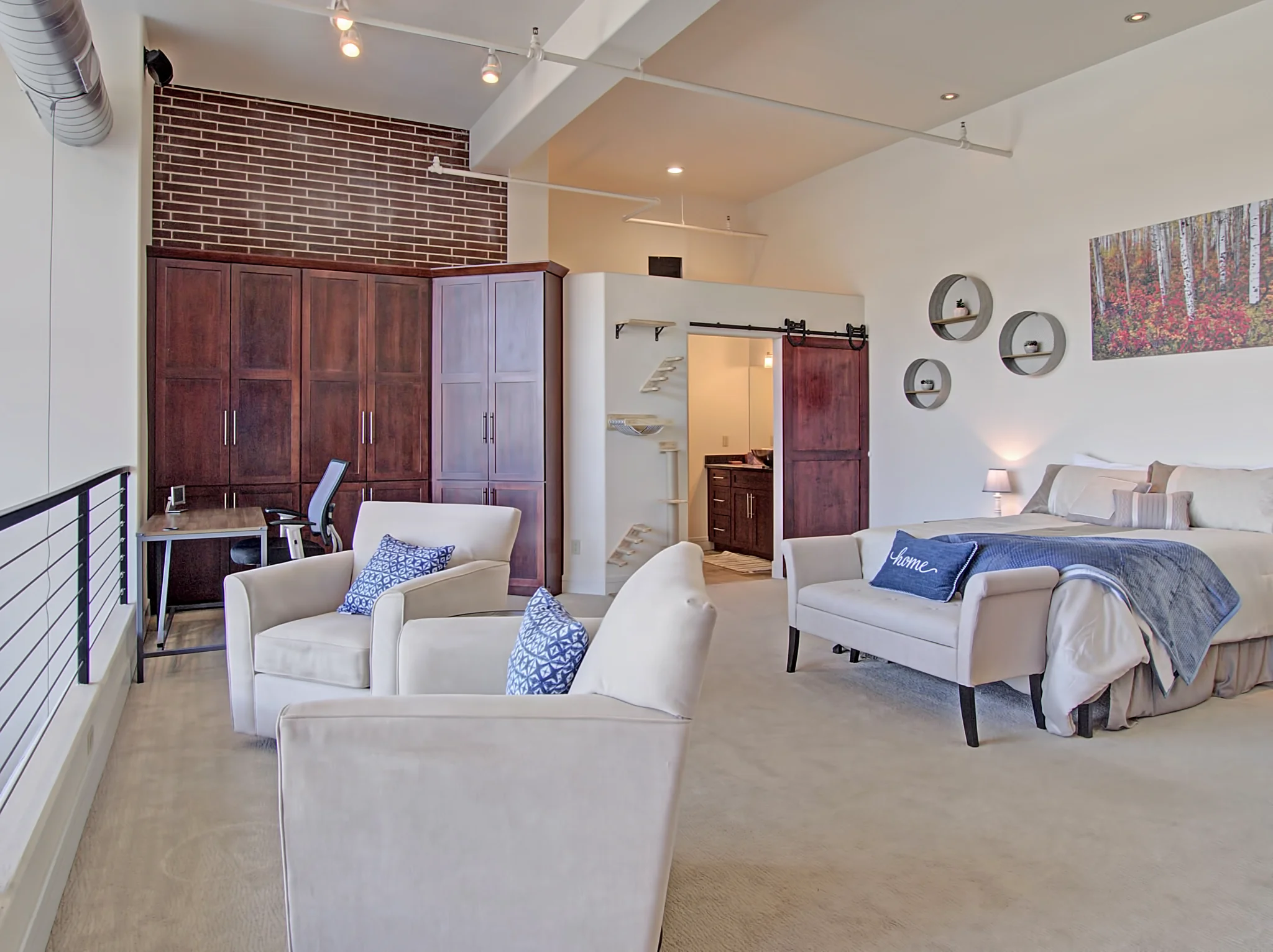 Upper-level bedroom and sitting area in Citywalk penthouse 1204, with exposed brick and loft railing